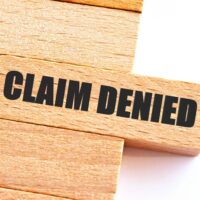 Wooden Blocks with the text:Claim Denied. phrase text under torn paper.Business,Insurance concept